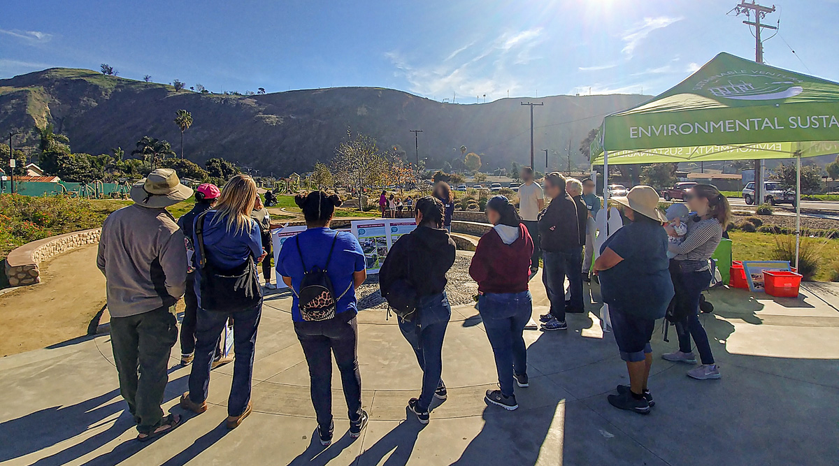 A group of people gathered around posters at an outdoor event.